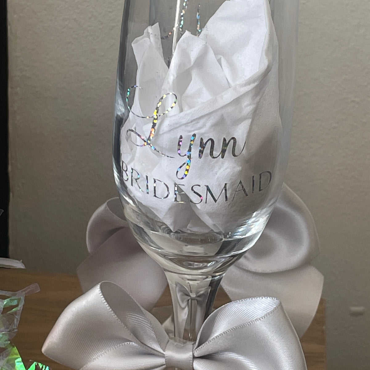 Personalized glass with 'Lynn Bridesmaid' text, decorated with white ribbons on a neutral background.