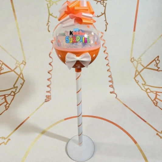 Toy figure on a stand with colorful design and text, against a decorative background.