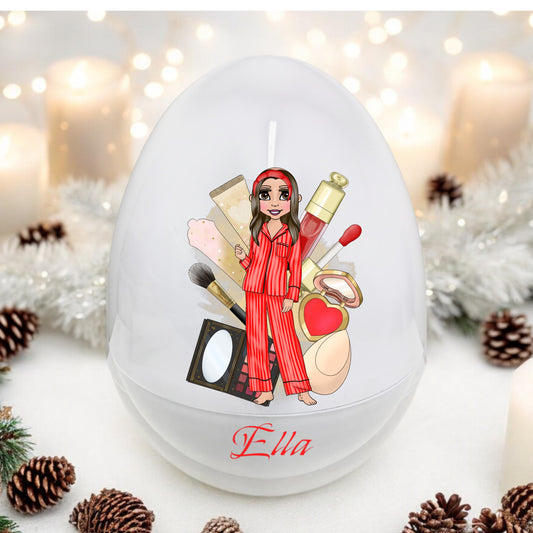 A decorated white egg with a personalized message and illustration of a character in pajamas surrounded by various items, such as makeup and a toy camera, with the name 'Ella' on the egg.