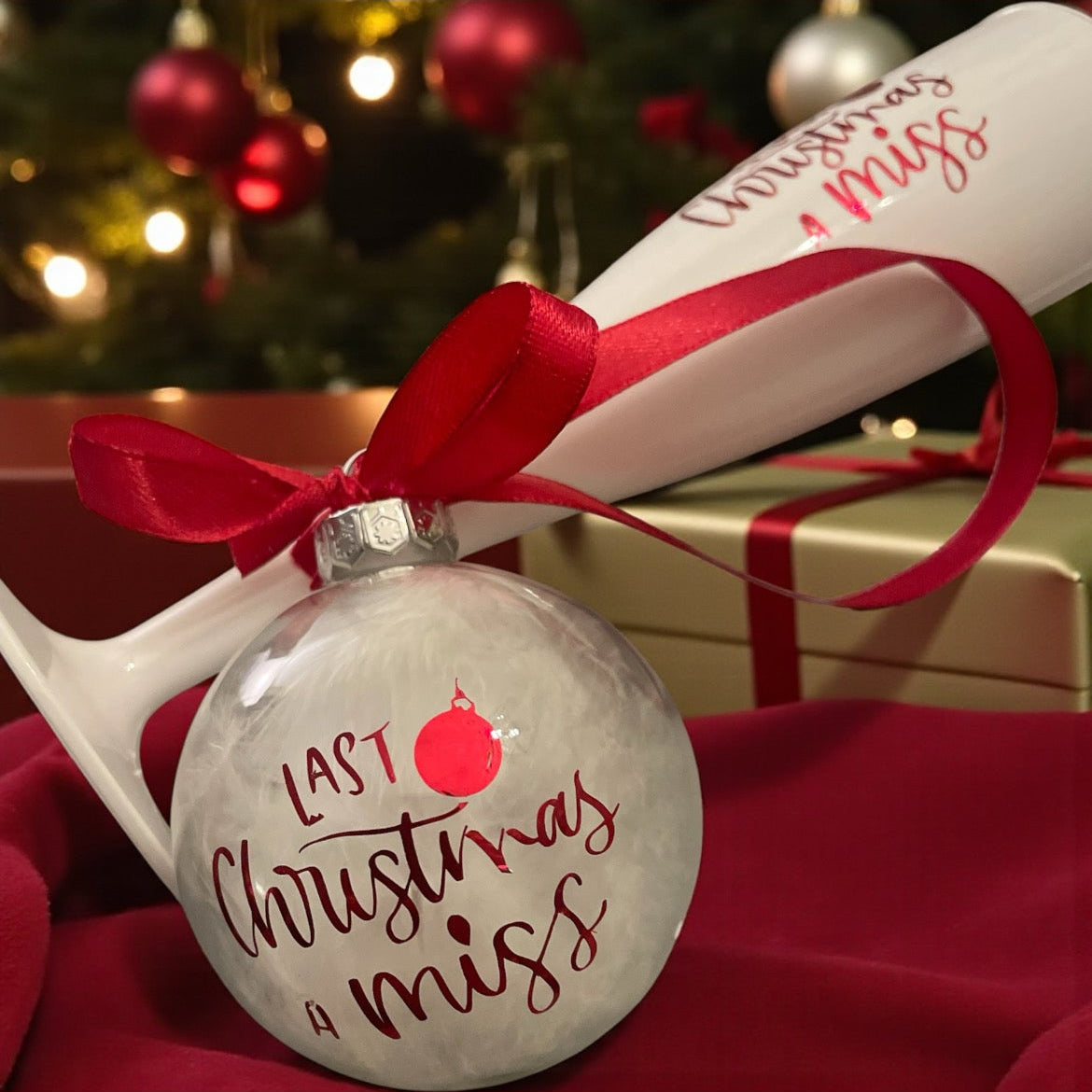 Christmas ornament with 'Last Christmas I missed' text and red ribbon on a festive background.