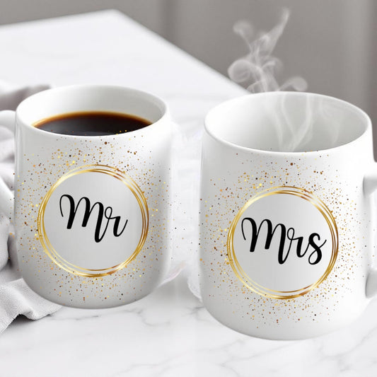 Two white mugs with 'Mr' and 'Mrs' labels on a marble surface.