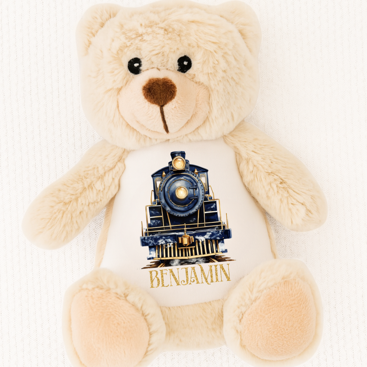 Beige teddy bear with a train design and 'Benjamin' text on a white background
