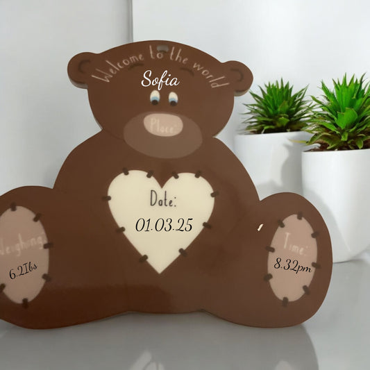 A wooden bear-shaped personalized keepsake with a heart shape in the center, displaying a welcome message, a baby's name, birth details, and a picture of the baby.