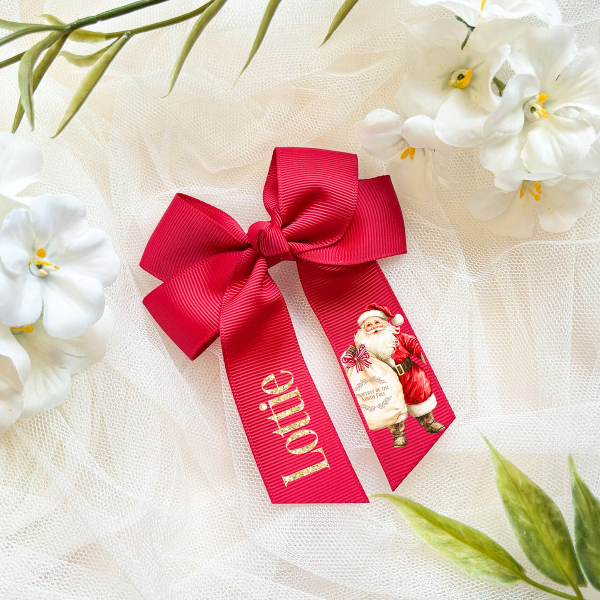 Red ribbon with Santa Claus design on a white fabric background with flowers