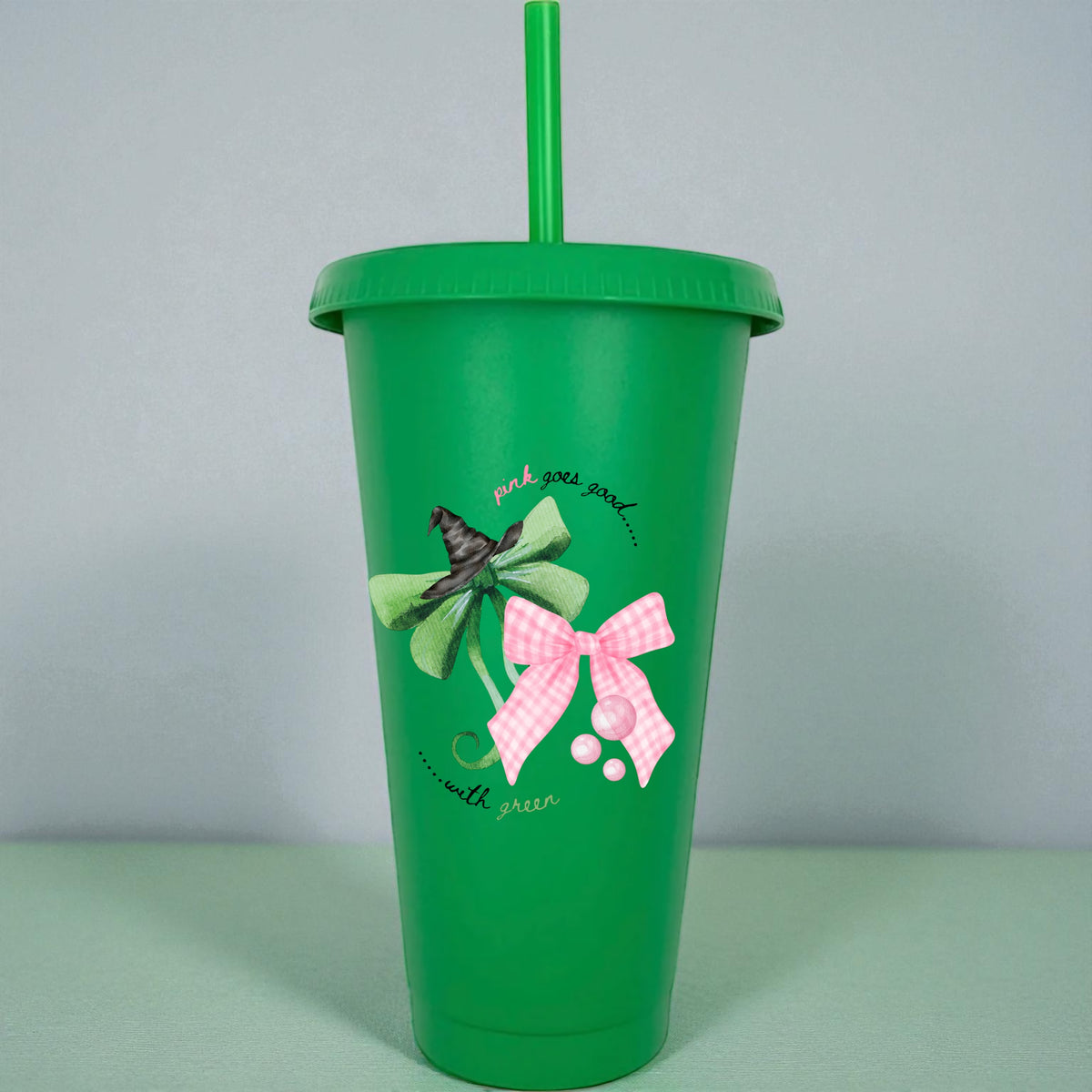 Green tumbler with decorative bows and text on a light gray background