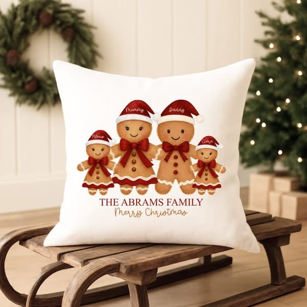 Decorative pillow with gingerbread family design on a wooden sled with Christmas decorations in the background.