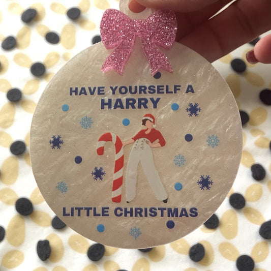 Round wooden ornament with a pink bow, Christmas-themed design, and text 'Have Yourself a Harry Little Christmas' on a patterned background.