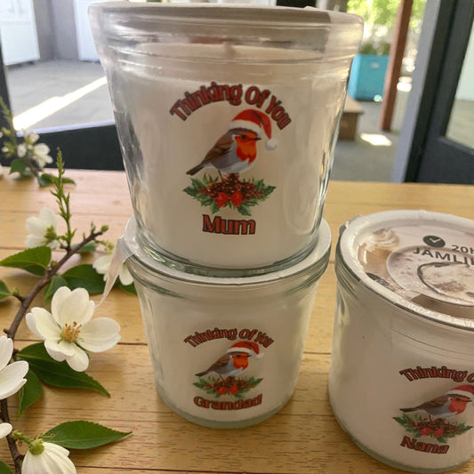 Stack of ceramic containers with 'Thinking Of You' and 'Mum' text on a wooden surface with flowers.