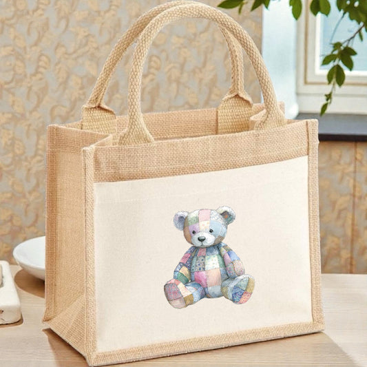 Jute bag with a patchwork teddy bear design on a wooden surface.